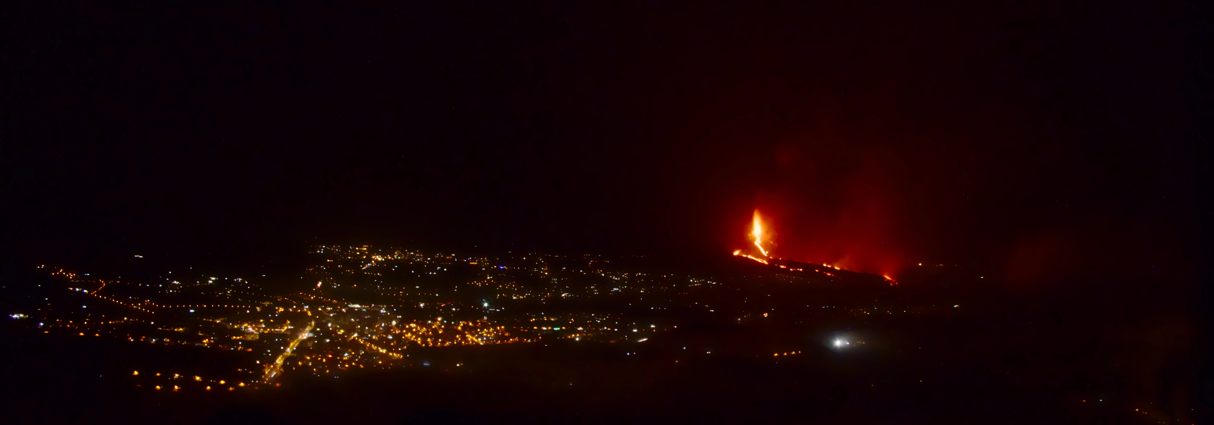 A nighttime panorama of Los Llanos city and Cumbe Vieja volcano in the background.